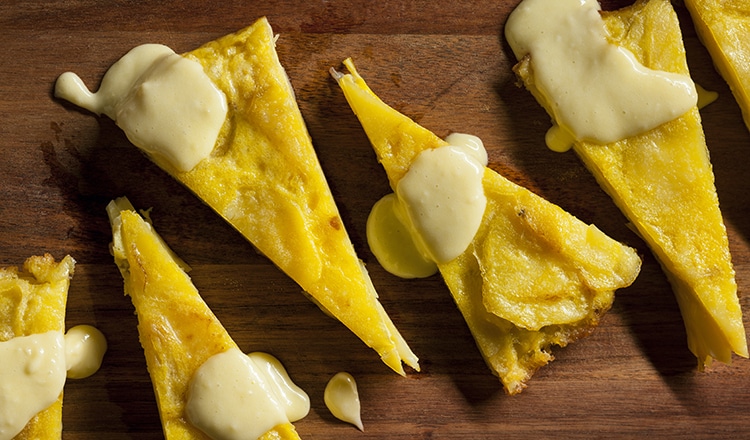 Spanish potato omelet topped with a white sauce