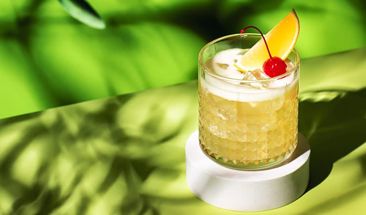 Whiskey Sour with a lime wedge and cherry