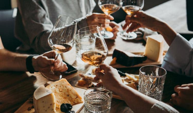 A group sharing wine and cheese at a table.