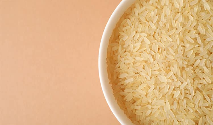raw rice in a white bowl on a peach background