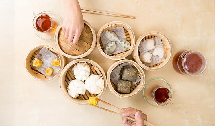Table full of dim sum in bamboo steamers.