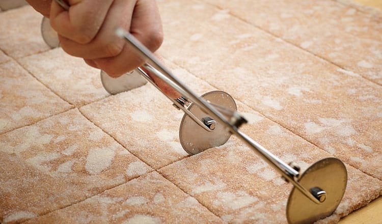 Cutting pastry dough with an accordian pastry wheel.
