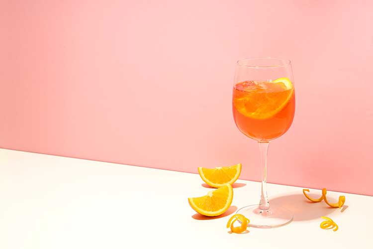 A spritz with orange peel against a pink wall