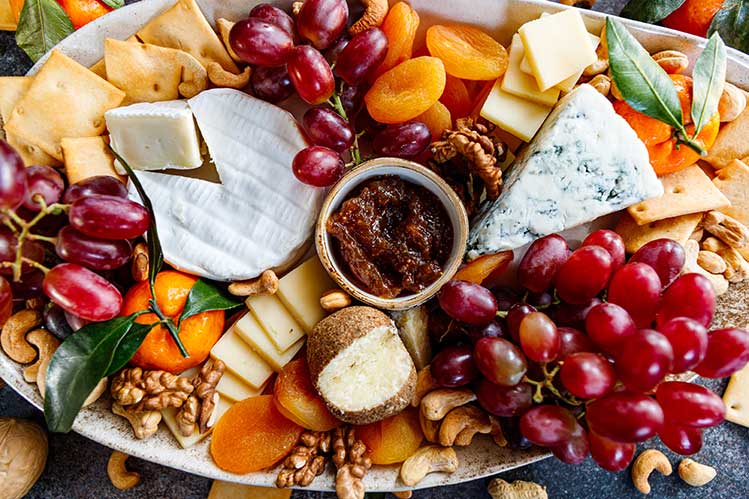 Cheese board with grapes, nuts, and dried fruit