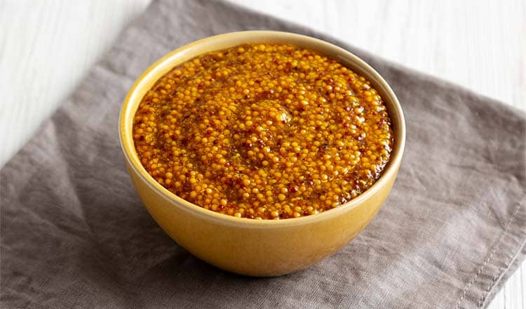 Grainy mustard in a yellow bowl