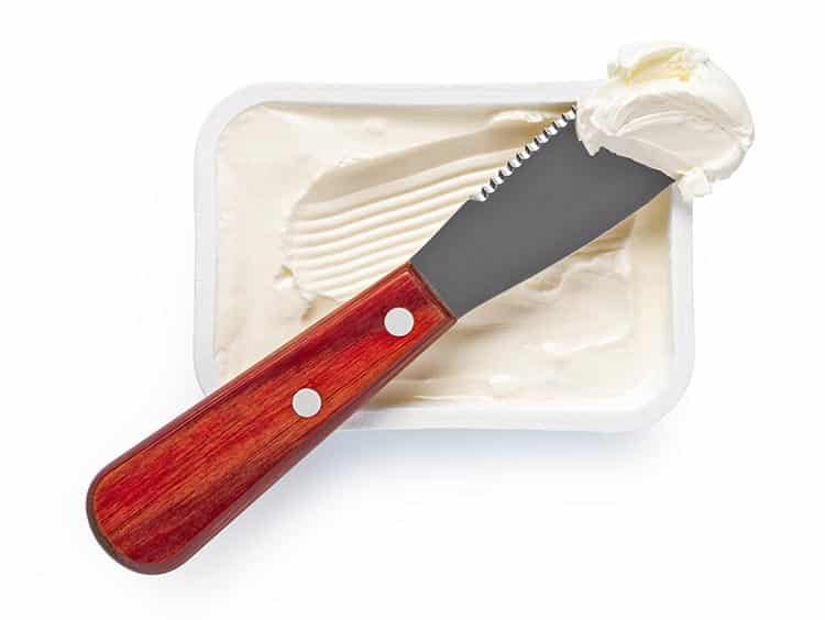 container of cream cheese with cream cheese on the spreader